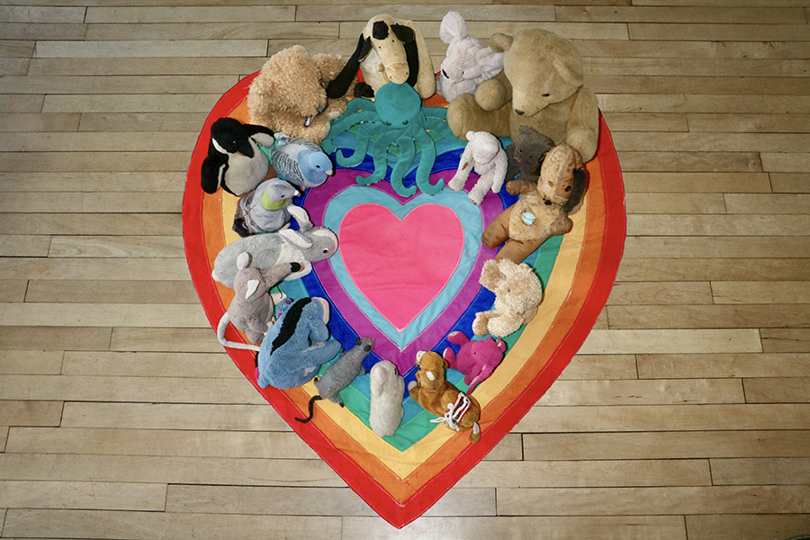 Image for Tending the heart an alternative grief ritual showing embracing grief toys gathering around a heart banner